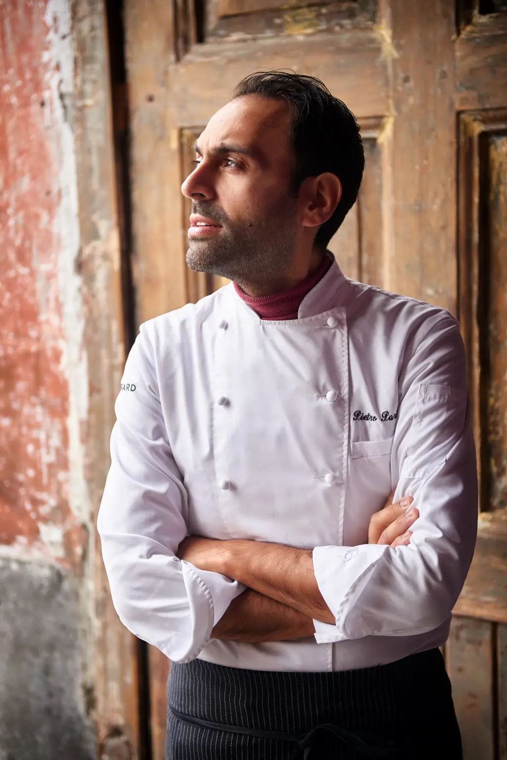 Pietro Parisi in divisa da chef davanti a un antico portone
