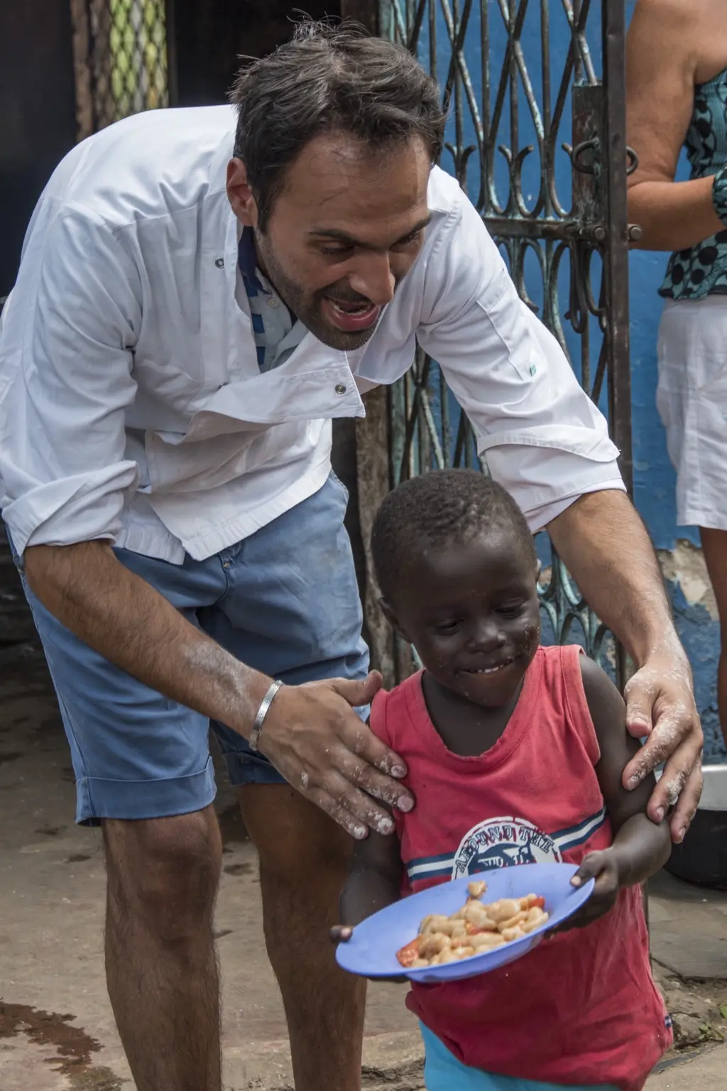 Pietro Parisi accompagna un bambino che porta un piatto di cibo