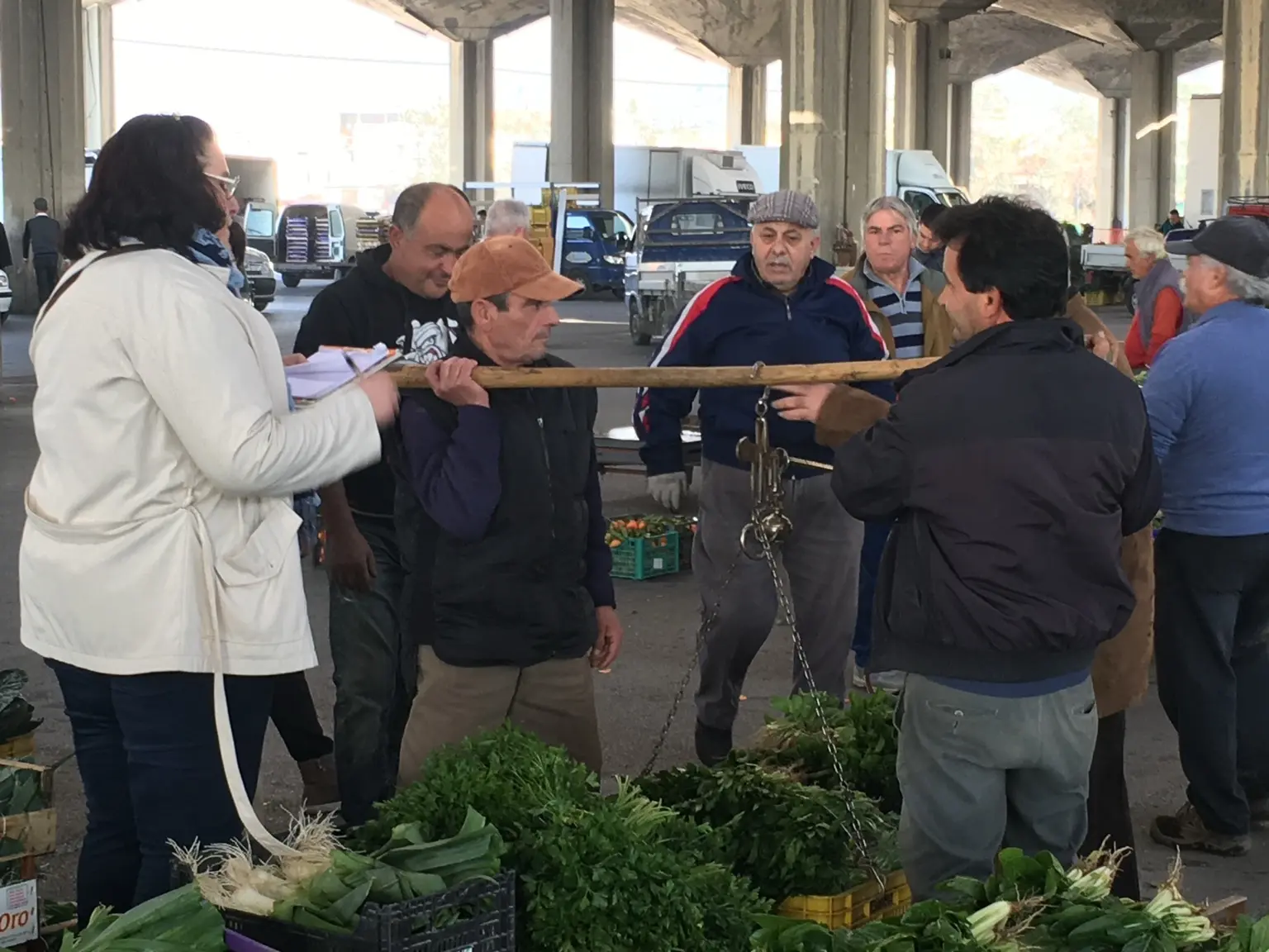Operatori del mercato pesano verdure fresche con una bilancia tradizionale