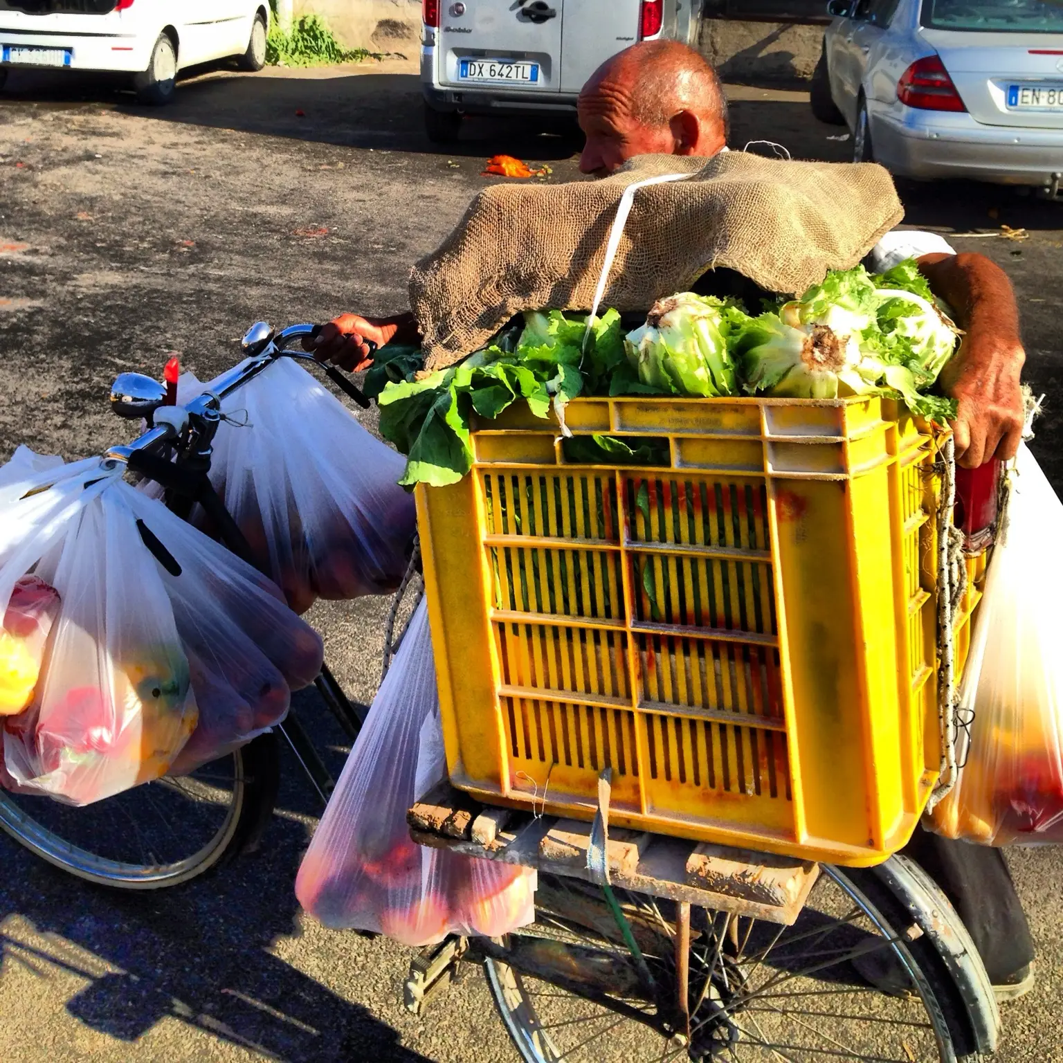 Venditore trasporta verdure fresche e borse su una bicicletta