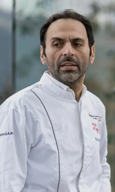 Pietro Parisi in divisa da chef davanti a un antico portone